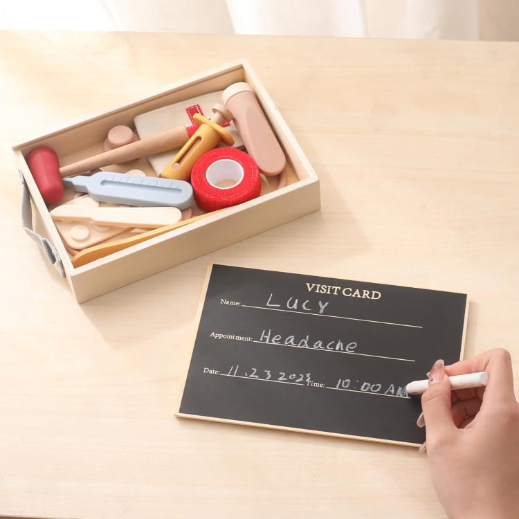 Wooden toy set in a box with a hand writing on a small blackboard.