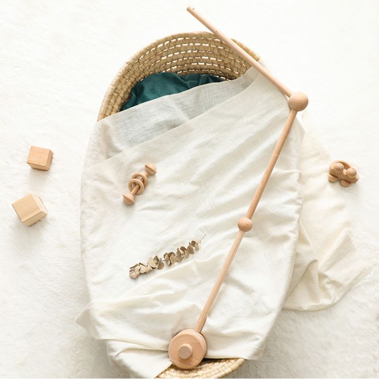 Baby crib with white blanket, wooden toys, and blocks on a light background