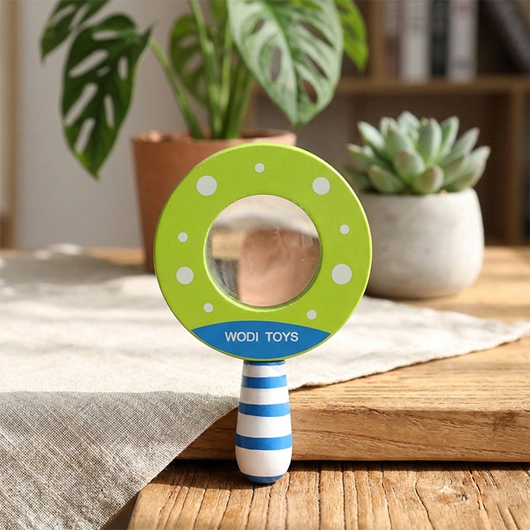 Magnifying Glass Toy | Green toy mirror with striped handle on a wooden surface with plants