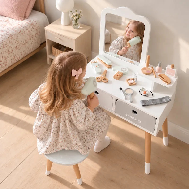 A young girl sits at a white vanity table with a mirror, playing with toy cosmetics and accessories. The room has light wood floors, a floral bed, and a bedside table.