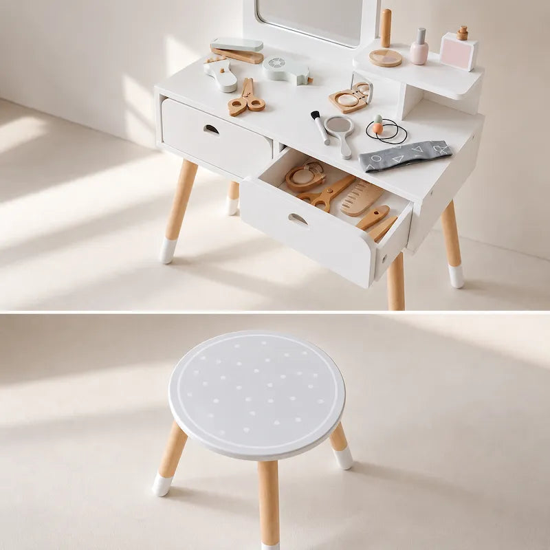 A children's wooden vanity table and matching stool set, shown in a bright, minimalist room. The top half shows the white vanity with light wood legs, drawers, and shelves styled with toy cosmetics.