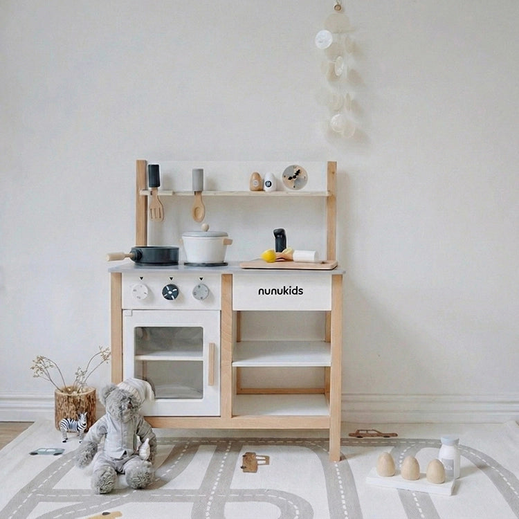 Nunukids Nordic Wooden Play Kitchen set with various accessories on a white floor.