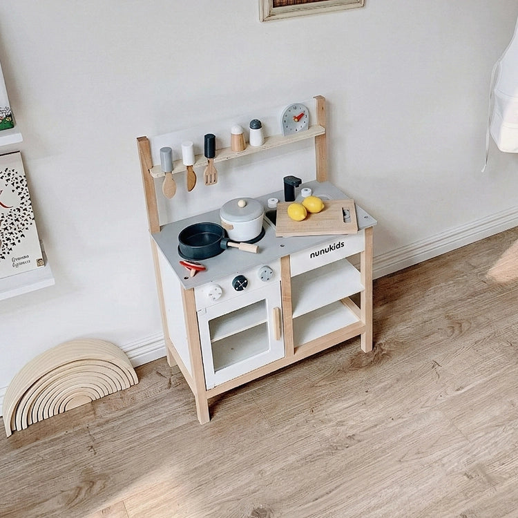 Nunukids Nordic Wooden Play Kitchen set up with various accessories on a wooden floor.