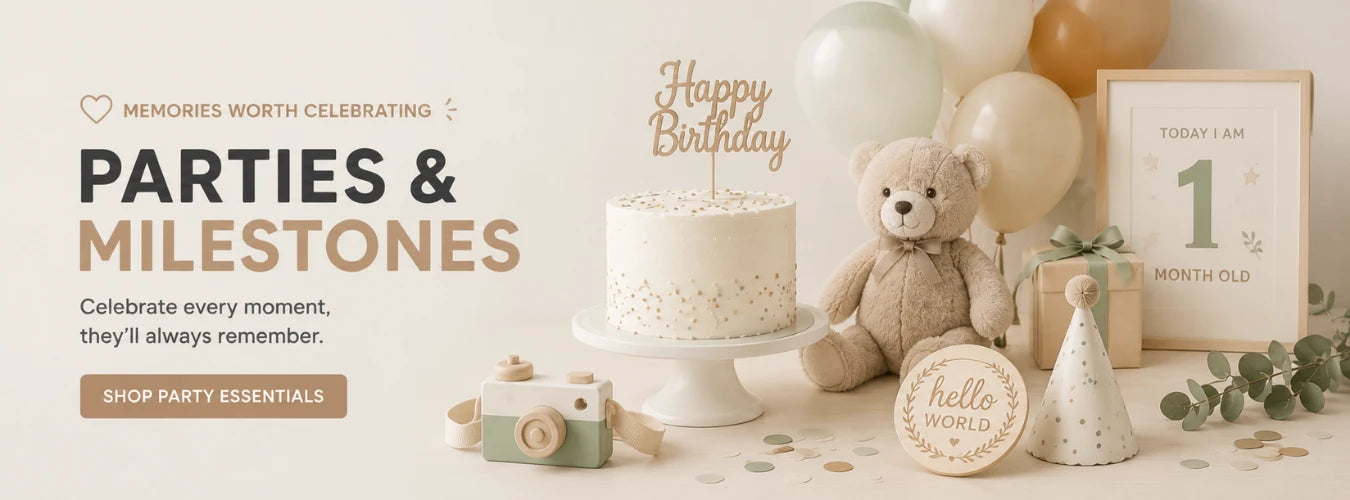 A styled birthday party scene with a white speckled cake on a stand, a teddy bear, balloons, a framed first birthday sign, a small gift box, and party decorations on a light beige background. Text on the left reads 'PARTIES & MILESTONES' with a 'SHOP PARTY ESSENTIALS' button.
