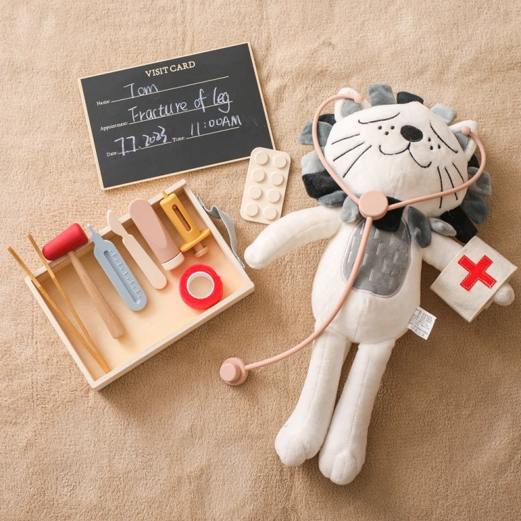 Plush toy lion with stethoscope next to a toy medical kit on a beige surface