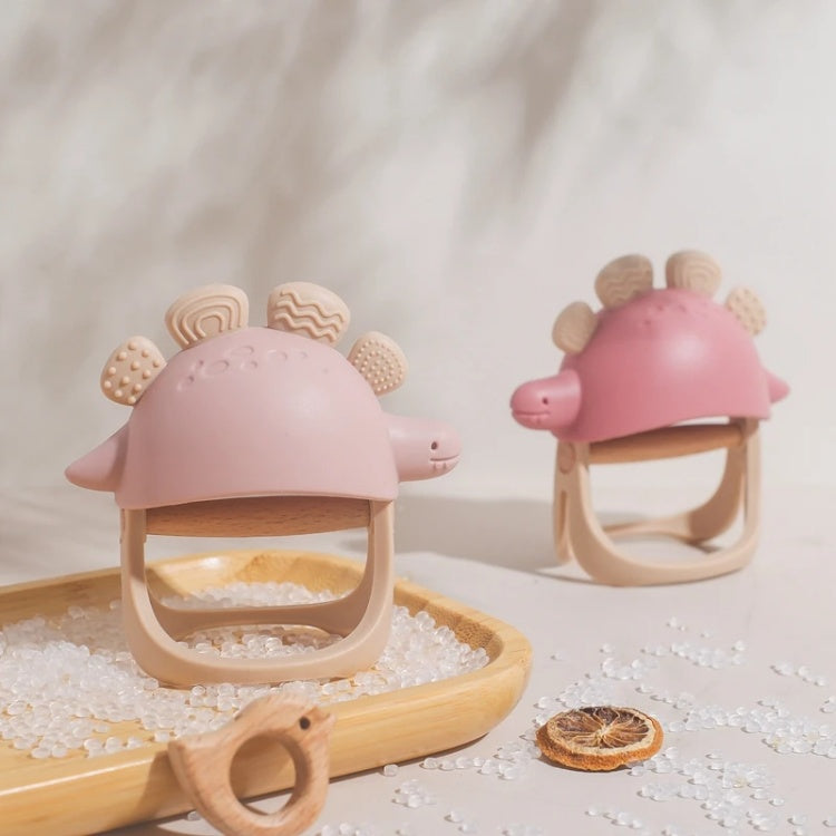 Two pink turtle-shaped baby teething toys on a light surface with a wooden tray.