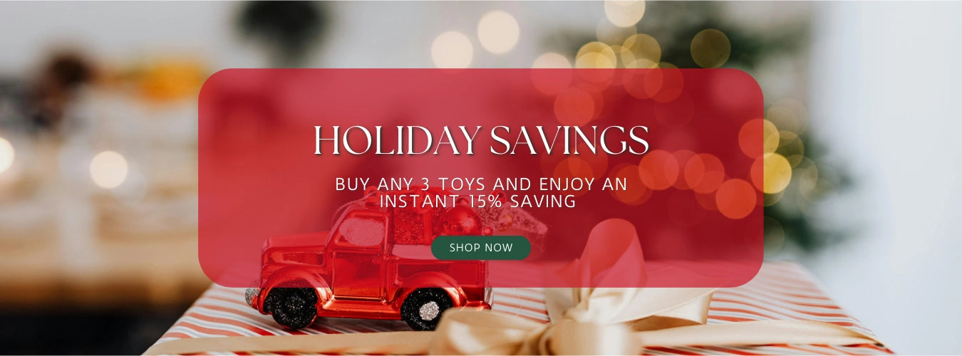 Red toy truck on a table with a 'Holiday Savings' promotional sign in the background.
